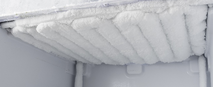 Interior de freezer com camada espessa de gelo acumulada nas paredes e no teto.