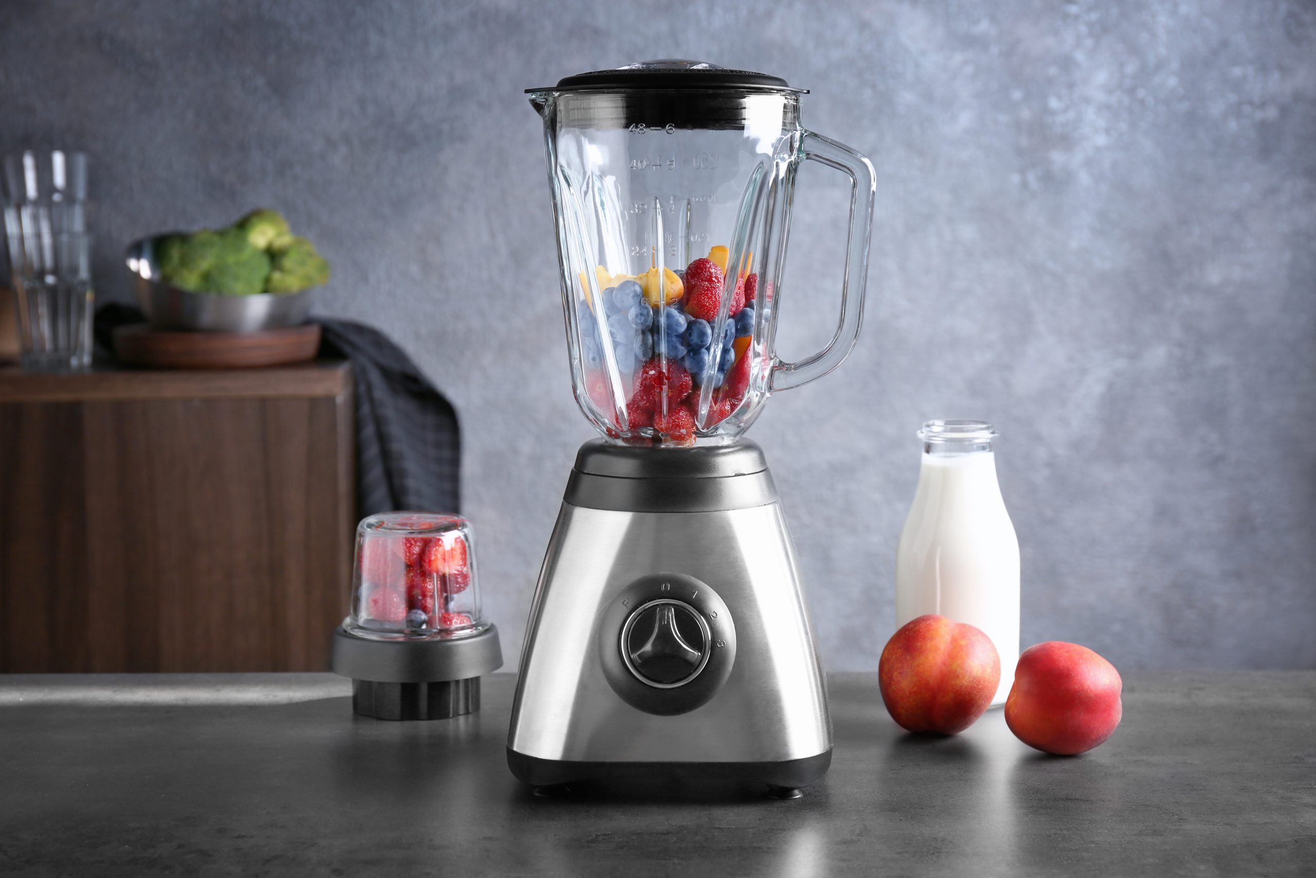 Na imagem, um liquidificador está centralizado na imagem com frutas vermelhas em seu interior.