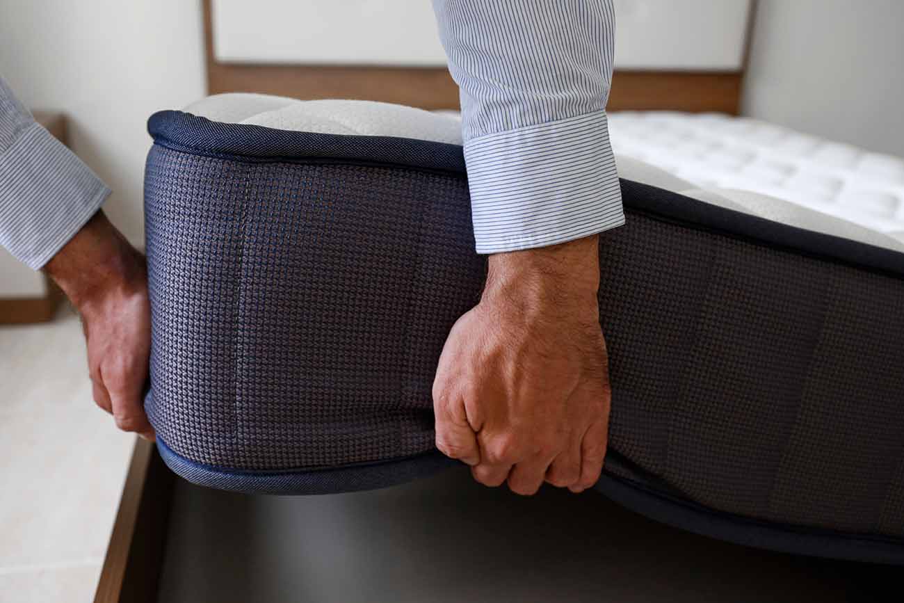 Imagem cortada de um homem levantando um colchão da cama